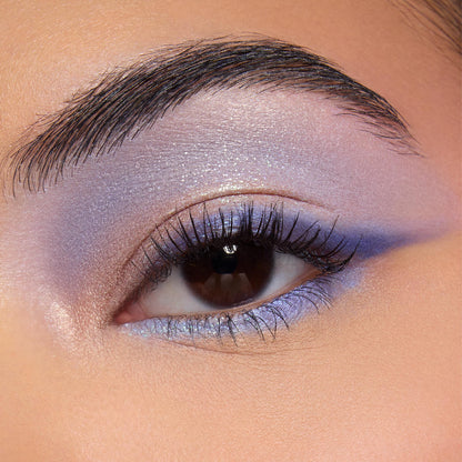 Shimmery lavender and periwinkle eye makeup showcases the Beach Dreamin’ ColourPop Shadow Palette, blending iridescent lilac across the lid with a soft crease fade and lower lash line accent in a studio close-up.
