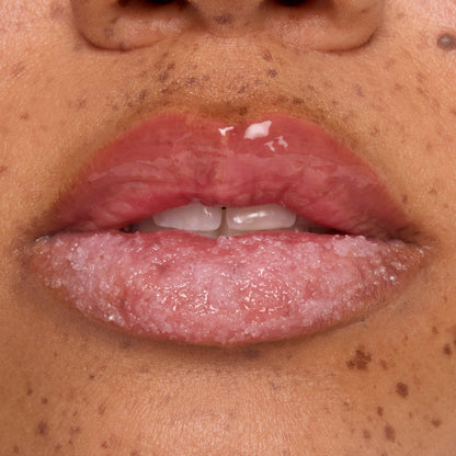 Glossy lips buffed with a candy cane sugar scrub while a hydrating mask coats the top lip, showcasing Colourpop Merriest Pout lip set in action, close-up on freckled skin to highlight smooth, exfoliated results.