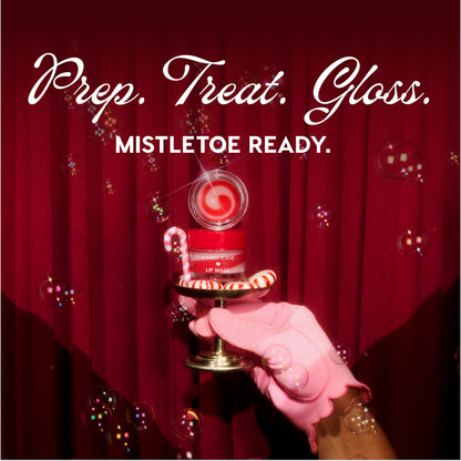 ColourPop Candy Cane Lip Mask jar with red‑white swirled balm opened, held on a small pedestal by a pink‑gloved hand beside a candy cane and peppermint, bubbles drifting before deep red curtains with the holiday headline Prep. Treat. Gloss. Mistletoe Ready.