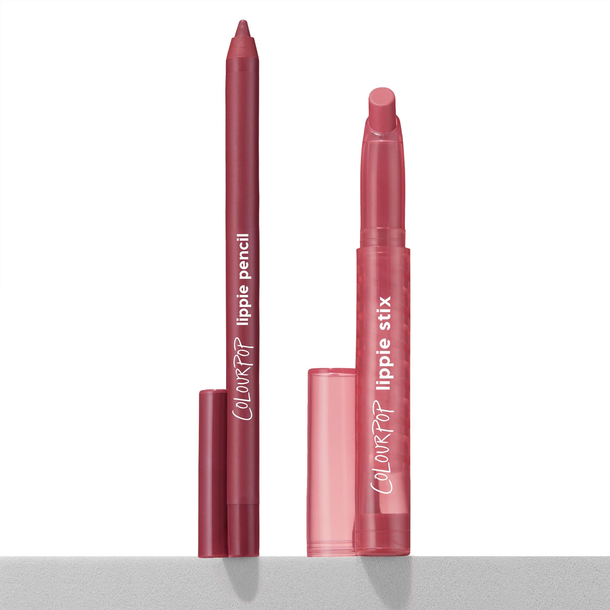 ColourPop Lippie Stix + Pencil Set, Got Pink? shade - matching rosy-pink lippie pencil and twist-up lippie stix standing uncapped with caps beside them, displayed upright on a light gray surface against a clean white background.