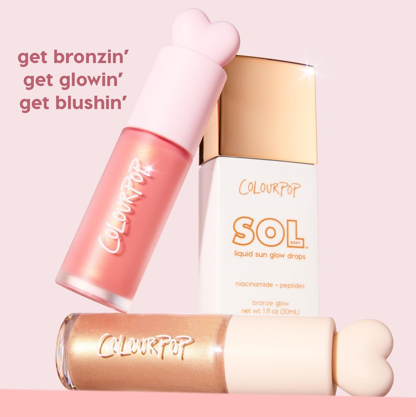 City Walk liquid blush by ColourPop, a rosy pink formula in a frosted bottle with a heart-shaped cap, tilts beside SOL Body liquid sun glow drops and a gold shimmer tube on a pastel pink background, promoting bronzing, glowing, and blushing.