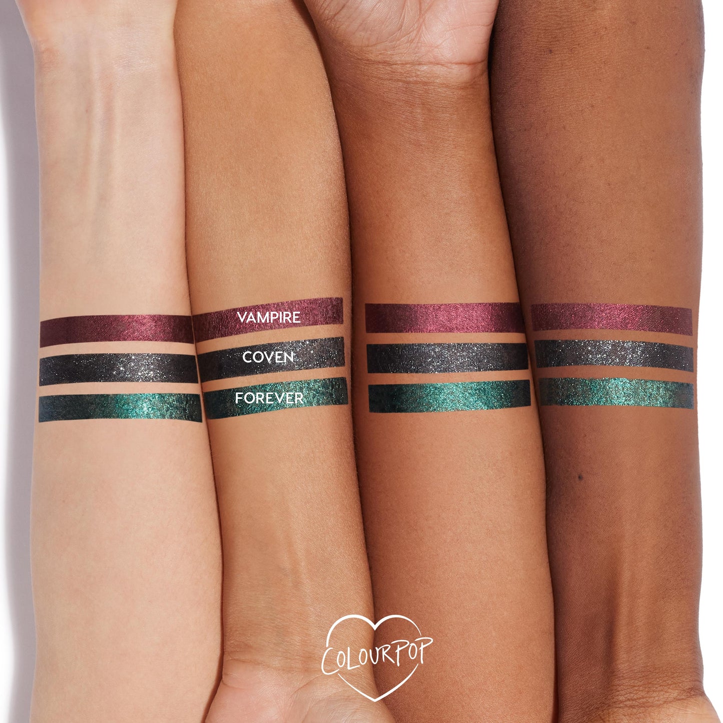 ColourPop Coven Graphix Ink Liner swatched on three forearms - a sparkly charcoal-black stripe centered between metallic burgundy Vampire and emerald-teal Forever - showing opaque payoff across multiple skin tones; ColourPop heart logo below.